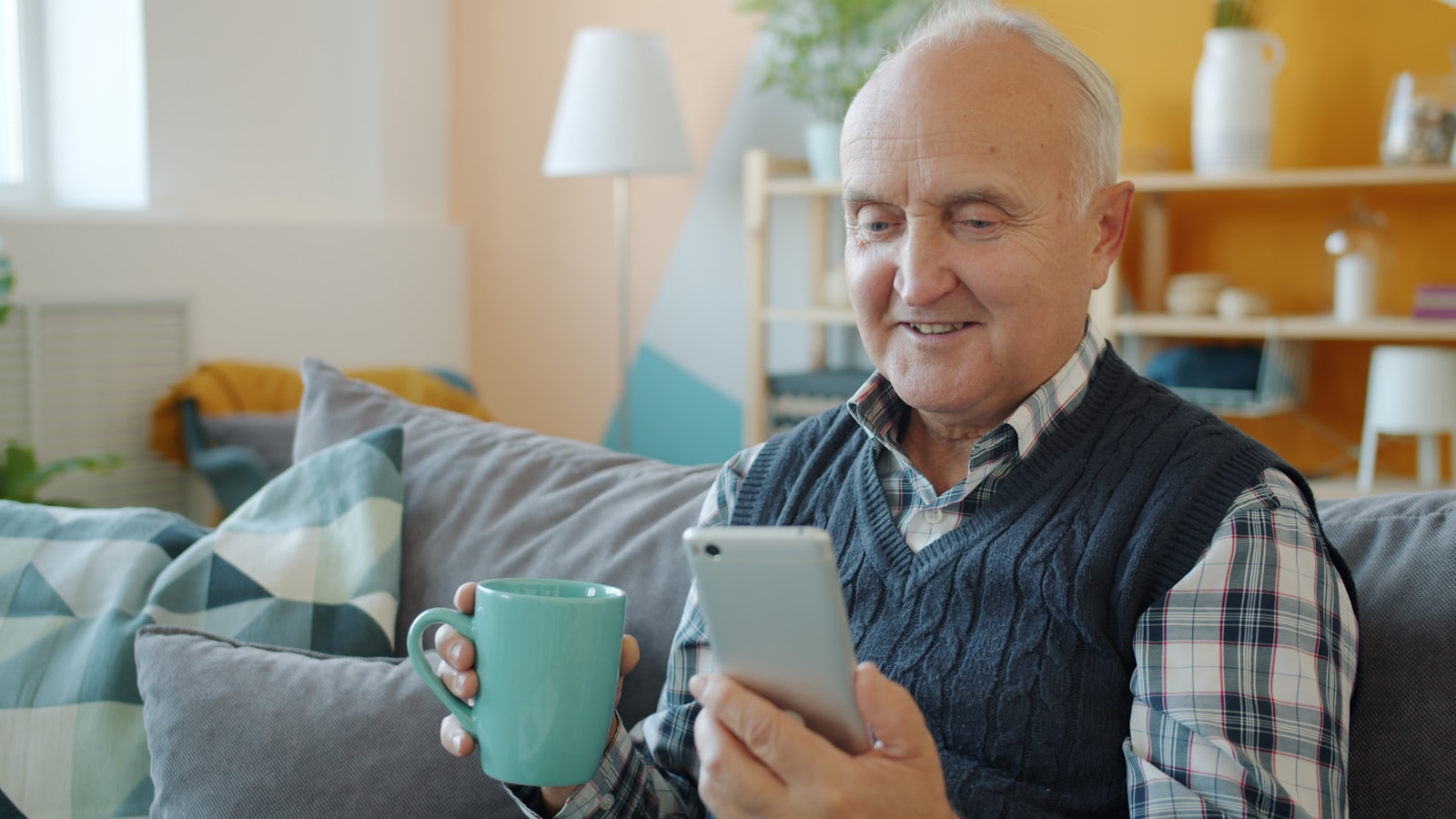 An older man smiling at his phone during a care call