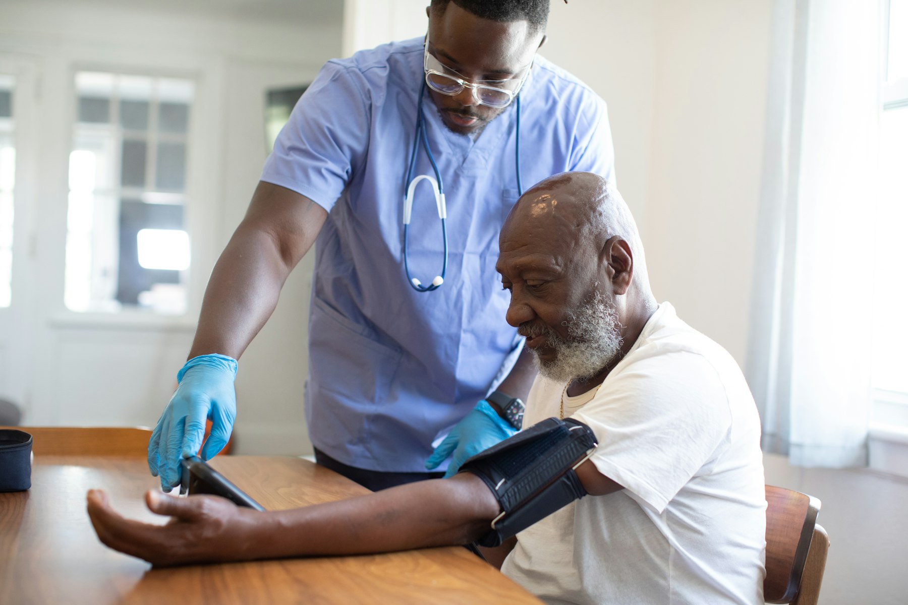 A nurse showing an older man his blood pressure reading at home